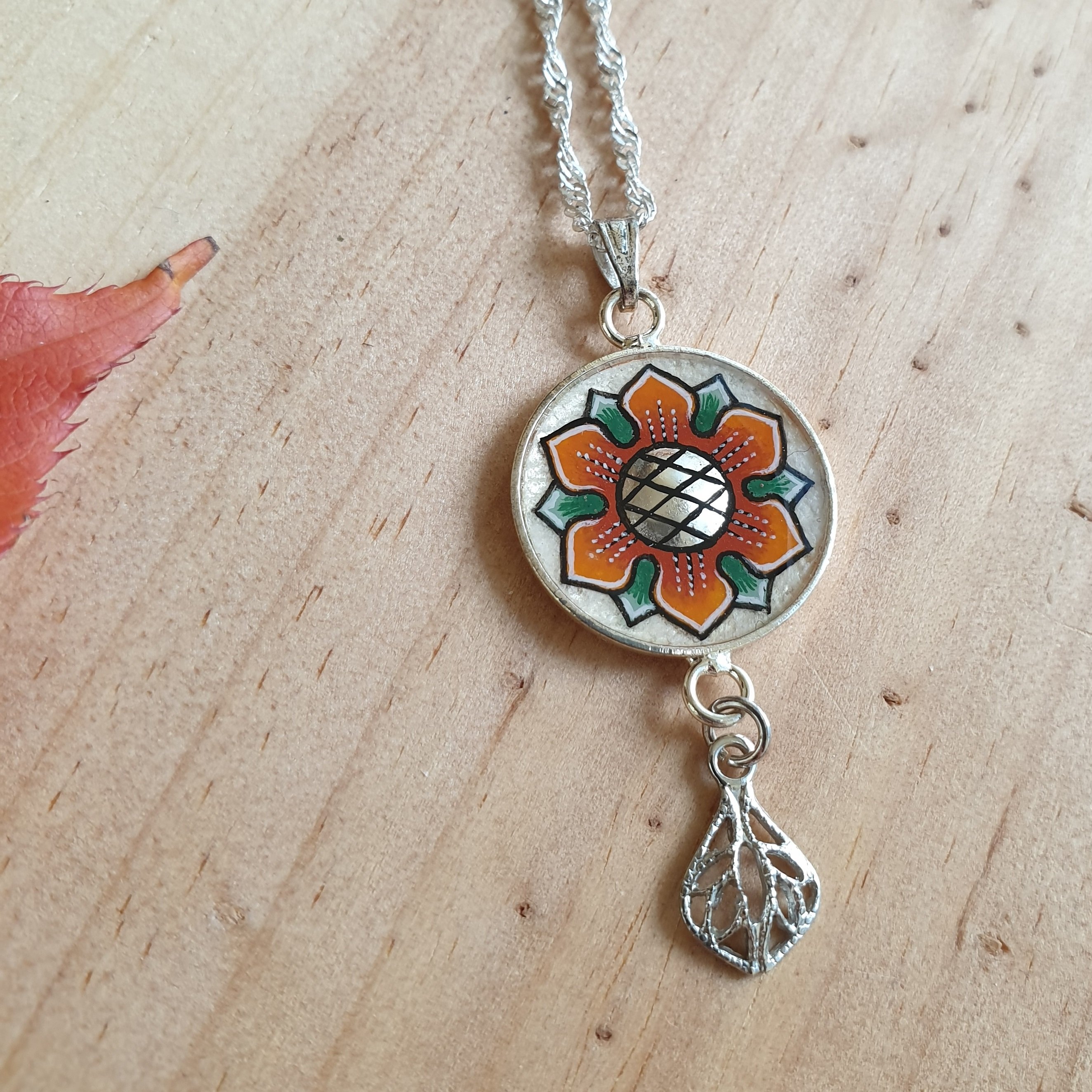 Colar com pingente de flores laranja/ouro sobre corrente de prata