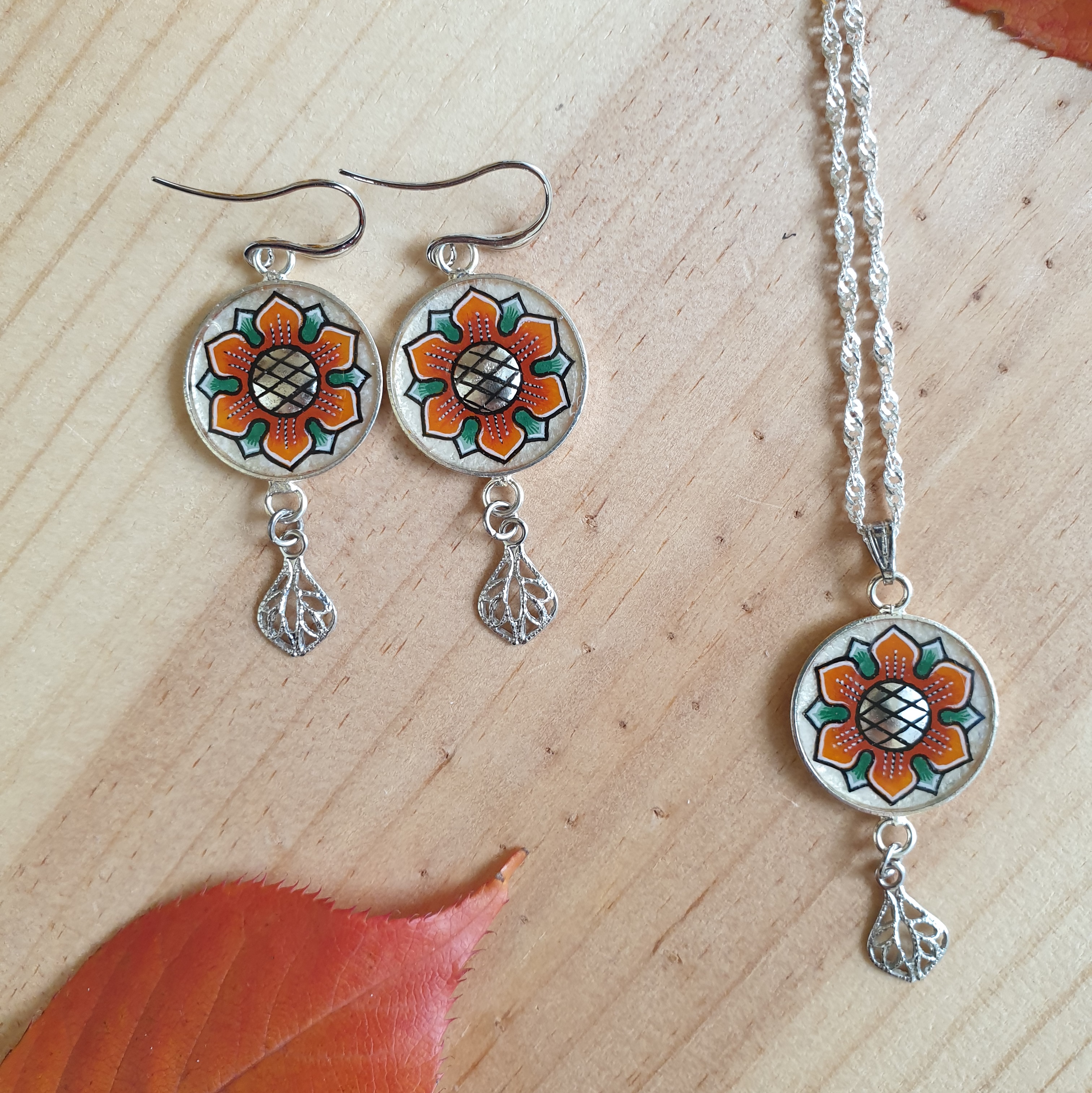 Colar com pingente de flores laranja/ouro sobre corrente de prata
