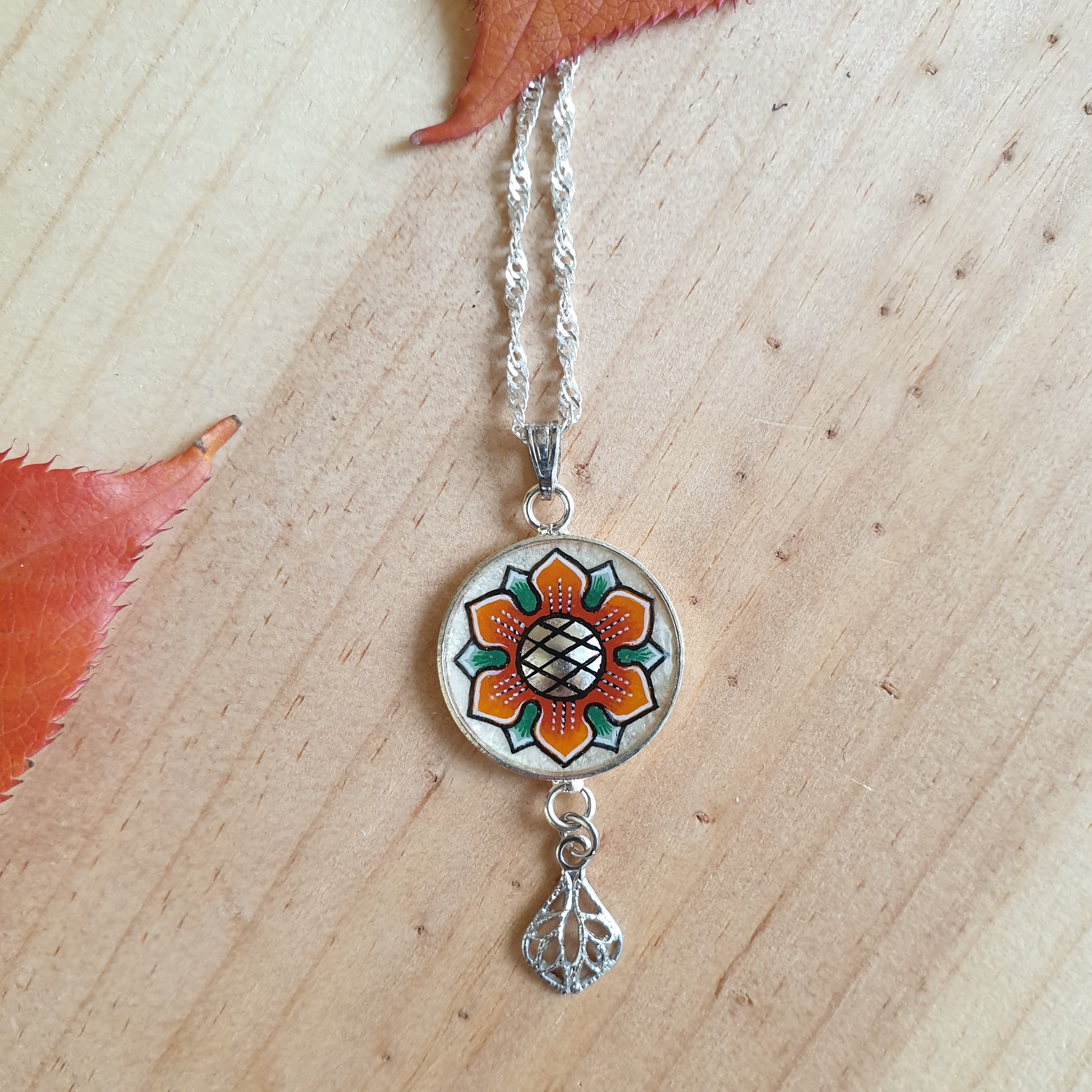 Colar com pingente de flores laranja/ouro sobre corrente de prata