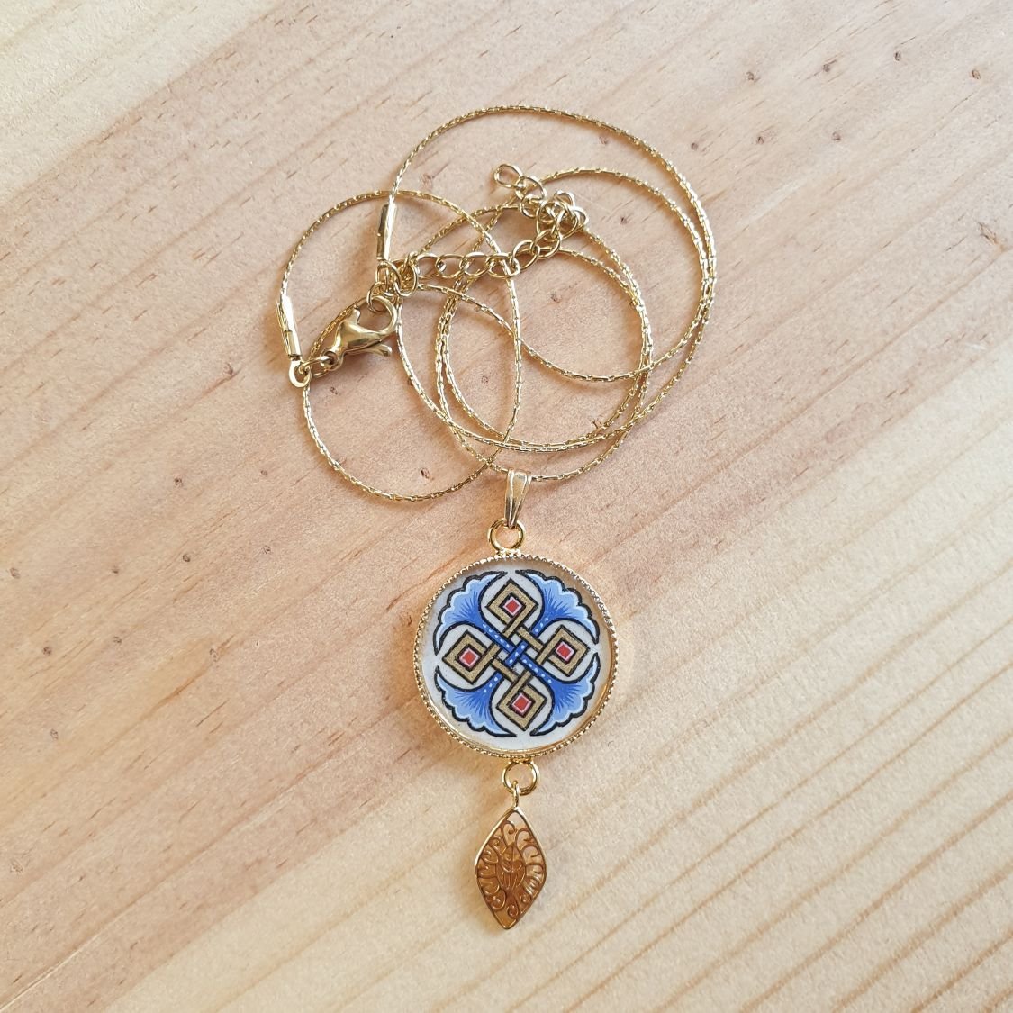 Colar pendente iluminado com palmetas azuis, entrelaçado dourado e vermelho sobre corrente dourada
