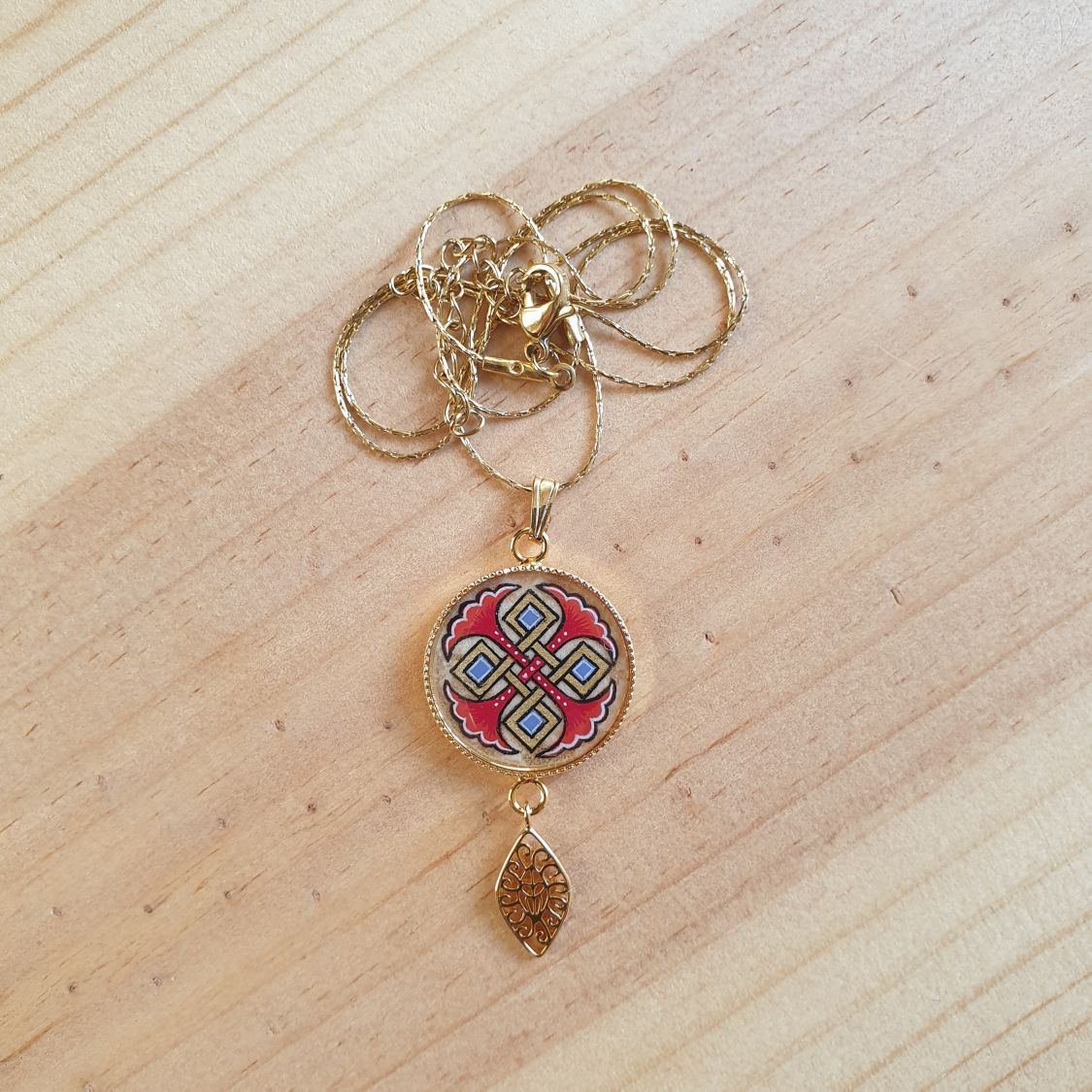 Colar pendente iluminado com palmetas azuis, entrelaçado dourado e vermelho sobre corrente dourada
