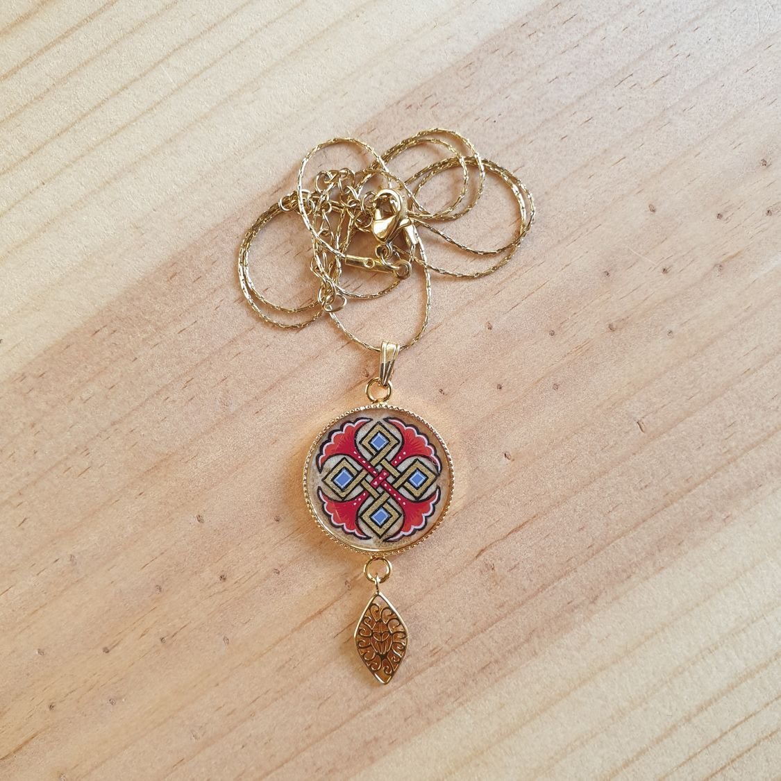 Colar pendente iluminado com palmetas azuis, entrelaçado dourado e vermelho sobre corrente dourada