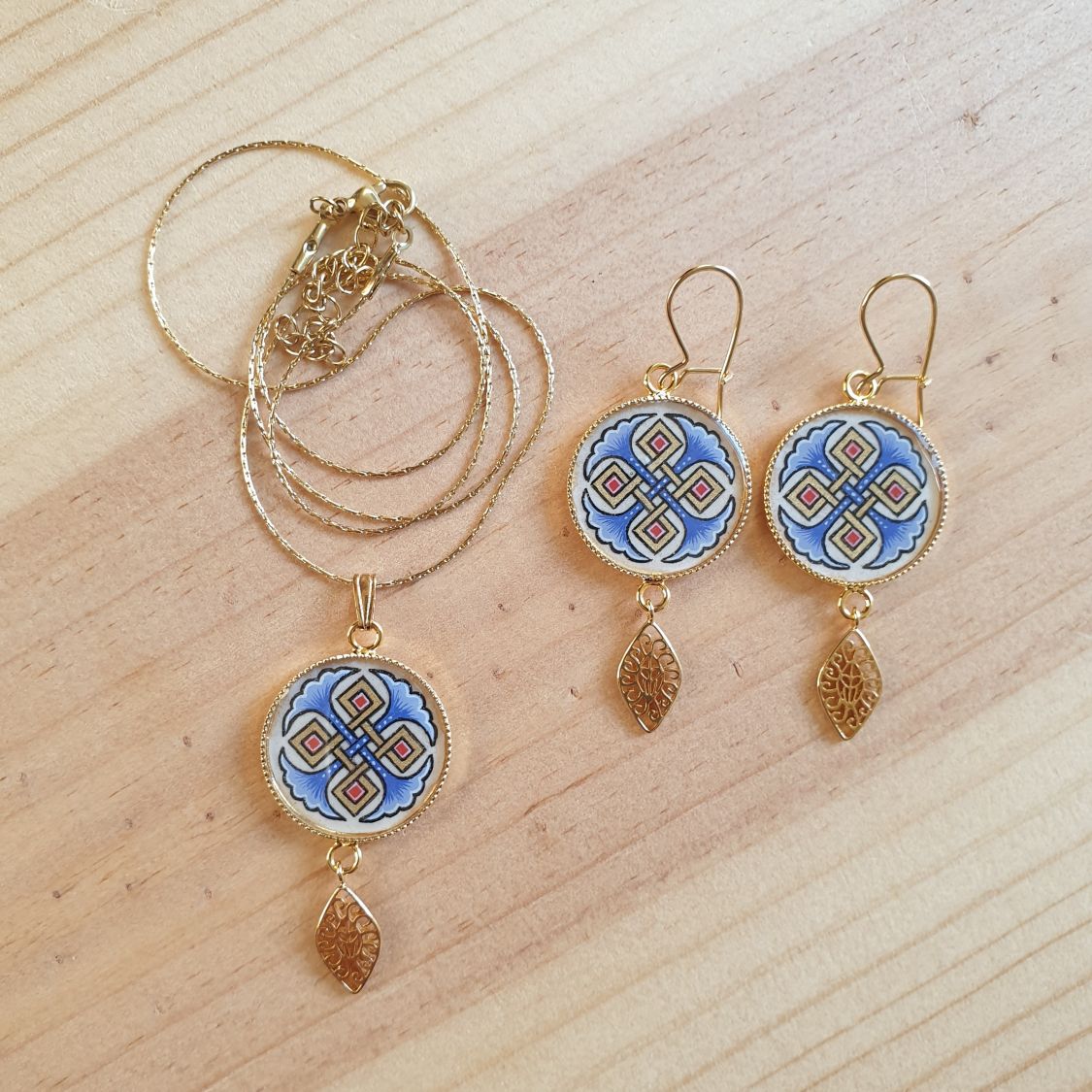 Colar pendente iluminado com palmetas azuis, entrelaçado dourado e vermelho sobre corrente dourada