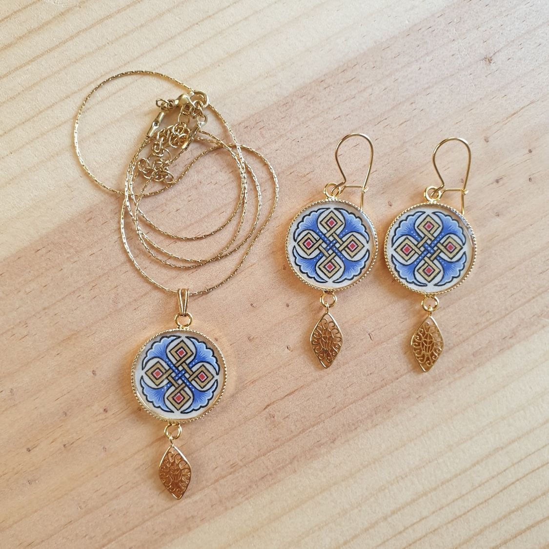 Colar pendente iluminado com palmetas azuis, entrelaçado dourado e vermelho sobre corrente dourada
