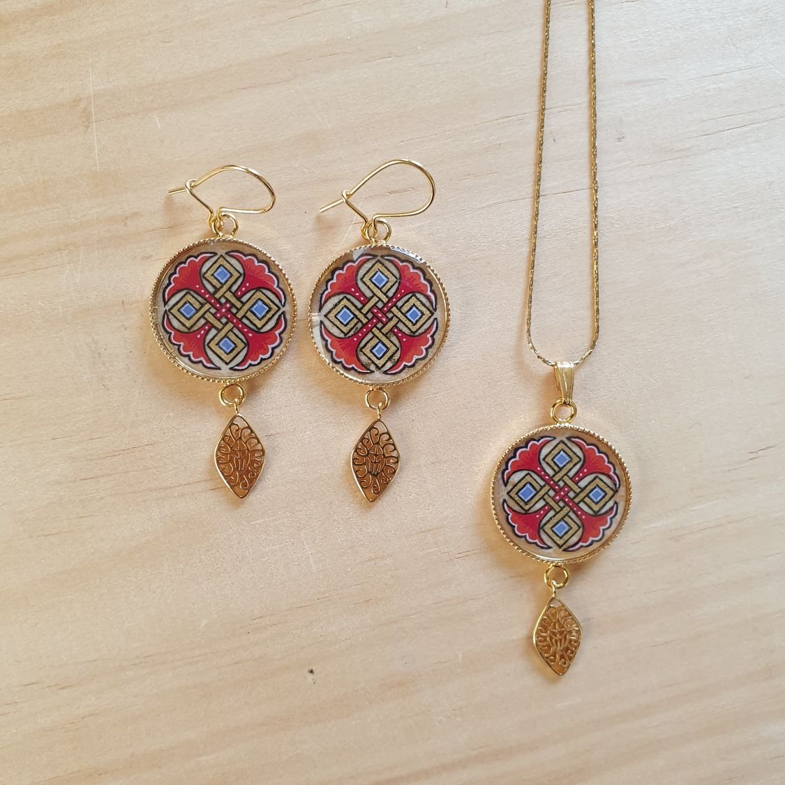 Colar pendente iluminado com palmetas azuis, entrelaçado dourado e vermelho sobre corrente dourada