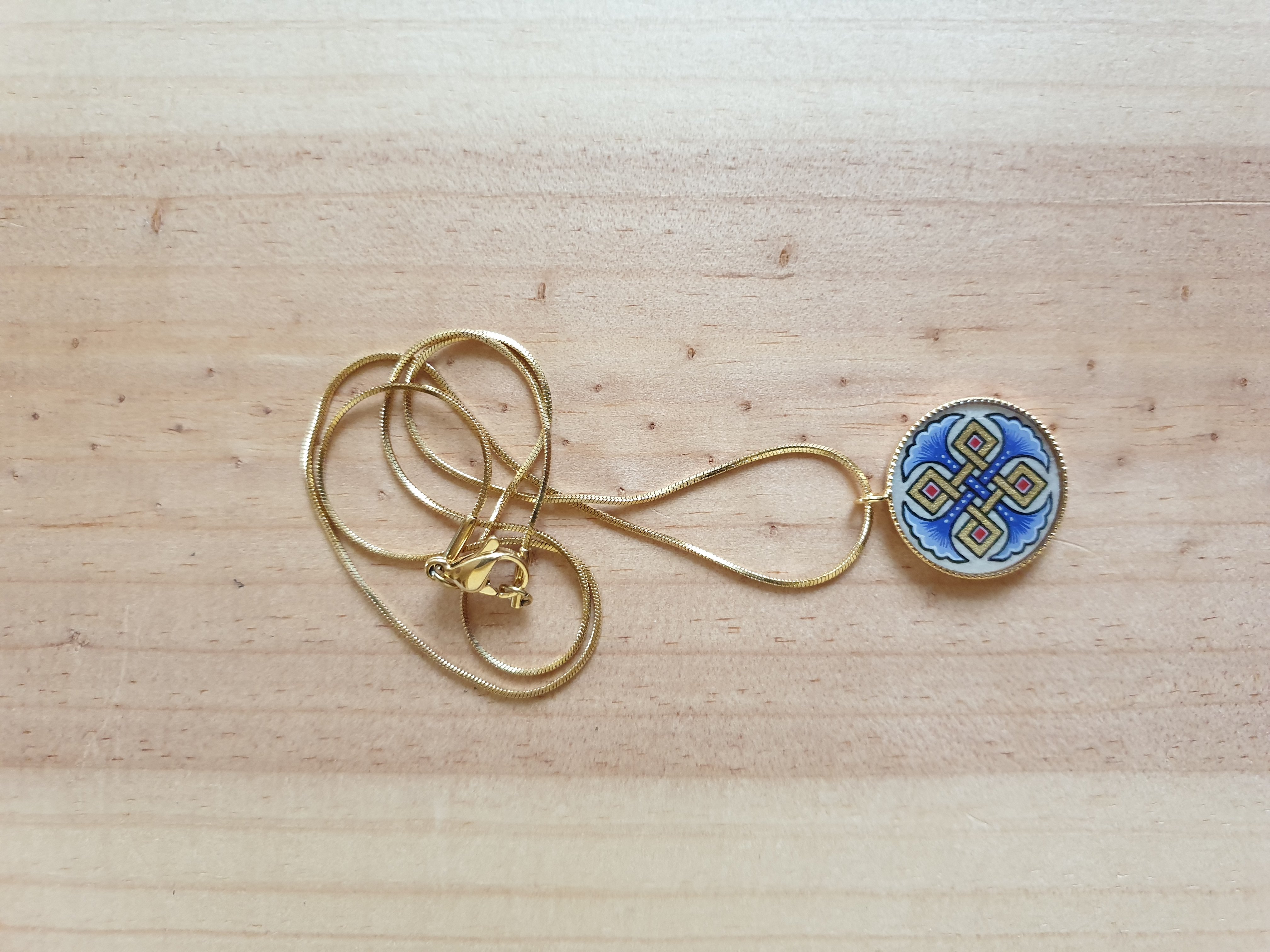 Colar pendente com palmetas azuis, entrelaçamento dourado e vermelho sobre corrente dourada
