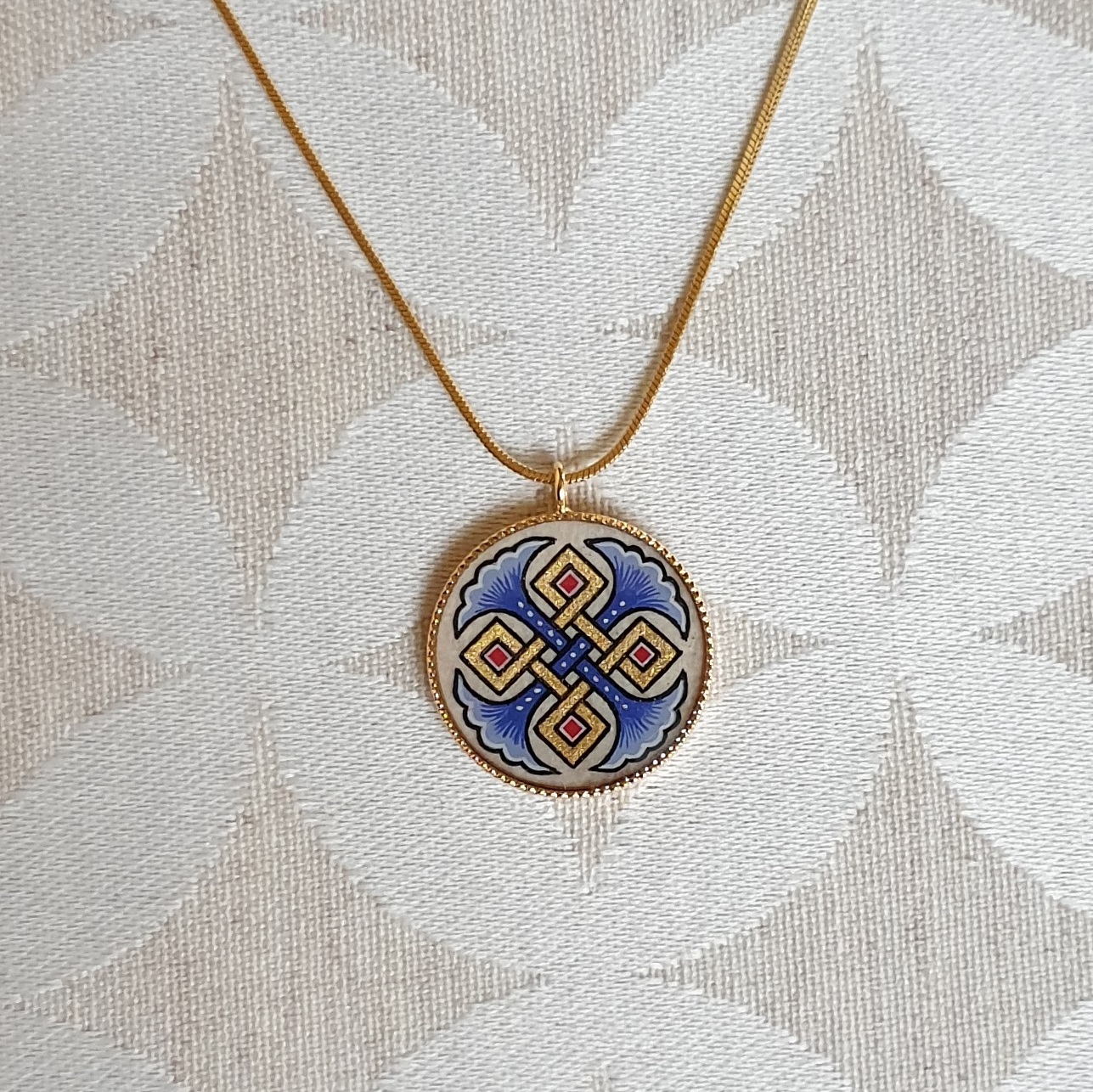 Colar pendente com palmetas azuis, entrelaçamento dourado e vermelho sobre corrente dourada