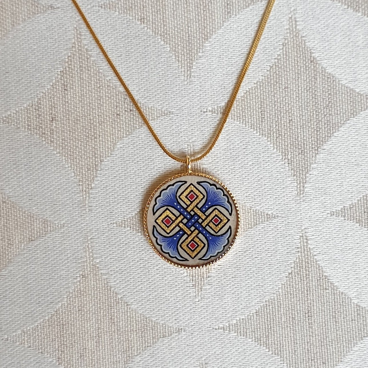 Colar pendente com palmetas azuis, entrelaçamento dourado e vermelho sobre corrente dourada