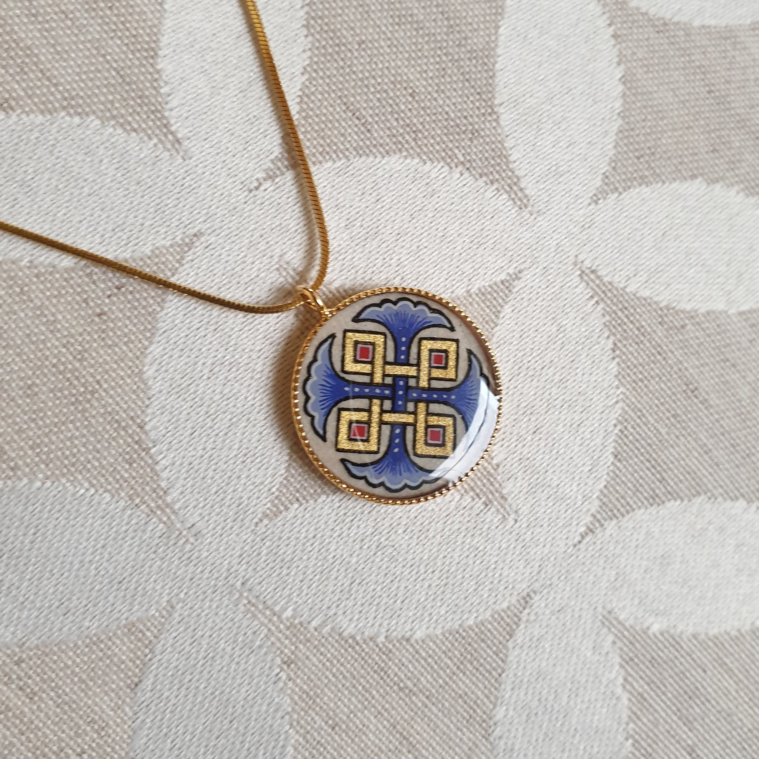 Colar pendente com palmetas azuis, entrela&ccedil;amento dourado e vermelho sobre corrente dourada