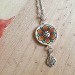 Colar com pingente de flores laranja/ouro sobre corrente de prata